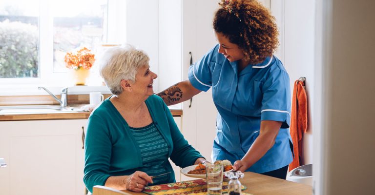 Smiliming care worker prepares meals as part of live-in care service